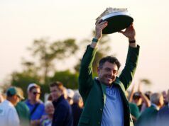 Rory McIlroy’s Decision Has Golf Fans Criticizing PGA Tour Man in a green jacket proudly raises a large circular model boat above his head at an outdoor crowd event, smiling for the camera.