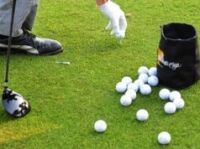 How To Go From Struggling to Break 90 to Shooting in the 70s Golfer placing a golf ball on the grass with a gloved hand, many balls scattered nearby and a bag nearby.