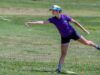More Than a Throw: The Surprising Rise of Disc Golf Athlete in a purple shirt and colorful cap mid-throw of a frisbee on a grassy field outdoors.