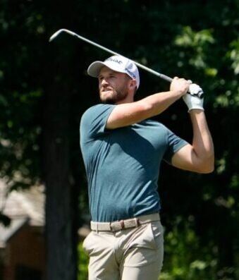 Wyndham Clark Blasts Crowd After Abuse at the US Open Male golfer in a teal shirt mid-swing with a golf club on a sunny course.