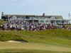 Shinnecock Hosts U.S. Open Amidst Preparations to Avoid Past Issues Large crowd of spectators gathered on a grassy hill outside a white clubhouse watching a golf event, with an American flag on the right.