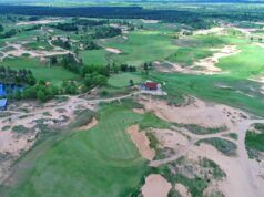 Golf Monthly reveals PGA Tour’s massive Australian Open partnership Aerial view of a golf course with green fairways, sand bunkers, and a lakeside clubhouse area nearby.