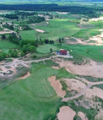 Golf Monthly reveals PGA Tour’s massive Australian Open partnership Aerial view of a golf course with green fairways, sand bunkers, and a lakeside clubhouse area nearby.