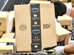 Golfer Battles Back Pain with Prime Day Recommendations Gloved hand gripping a cardboard Amazon Prime box in a warehouse setting.