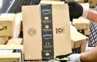 Golfer Battles Back Pain with Prime Day Recommendations Gloved hand gripping a cardboard Amazon Prime box in a warehouse setting.