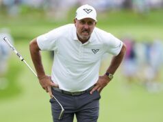 Phil Mickelson’s Latest Controversy Will Test Golf’s Patience Male golfer in a white polo and cap stands with hands on hips on a lush green course, holding a club.