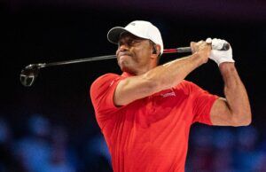 Tiger Woods Introduces Major PGA Tour Reforms in Rare Appearance Male golfer in a red polo shirt and white cap mid-swing, gripping a golf club against a dark background.