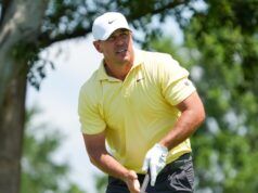Koepka Fires Eight Birdies, Takes Early Canadian Open Lead Golfer in a pale yellow polo and white cap mid-swing on a sunny golf course
