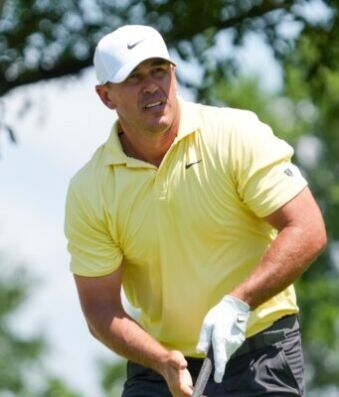 Koepka Fires Eight Birdies, Takes Early Canadian Open Lead Golfer in a pale yellow polo and white cap mid-swing on a sunny golf course