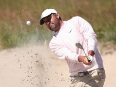 Scheffler Favored to Win 2026 U.S. Open, But Longest Odds Since 2023 Golfer in a light pink sweater and white cap hitting from a bunker as sand sprays into the air near a golf ball and club