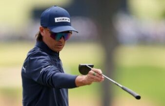 Fowler’s Putter Experiments Continue at John Deere Classic Golfer wearing a navy Cobra cap and mirrored sunglasses, gripping a golf club mid-swing.