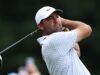 Scottie Scheffler Targets Historic Double Win in Scotland Male golfer in a white cap swinging a golf club, focused on the ball, on a green course backdrop.