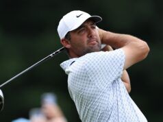 Scottie Scheffler Targets Historic Double Win in Scotland Male golfer in a white cap swinging a golf club, focused on the ball, on a green course backdrop.