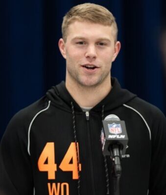 Awesome Moment College Star Is Drafted While Playing Golf Athlete in a black hoodie with orange '44' speaks at a press conference, microphone with NFL logo in front of him.