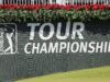 As LIV Golf Tension Eases, A New Civil War Breaks Out PGA TOUR Championship banner on a dark wall with bright red flowers along the top edge and a PGA TOUR logo on the left side.