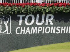 As LIV Golf Tension Eases, A New Civil War Breaks Out PGA TOUR Championship banner on a dark wall with bright red flowers along the top edge and a PGA TOUR logo on the left side.