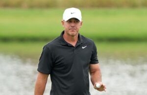 Koepka Drops Brutal Truth About LIV Golf’s Real Weakness Man in a black polo shirt and white Nike cap holding a golf ball on a golf course field.